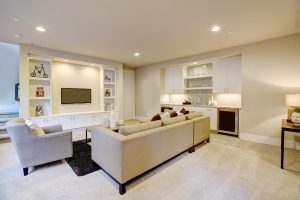 Chic basement features a gray sectional facing a white built-in tv cabinet and wet bar mounted to a wall. Northwest USA